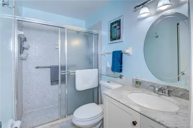 a bathroom with a granite countertop sink toilet a mirror a vanity and shower