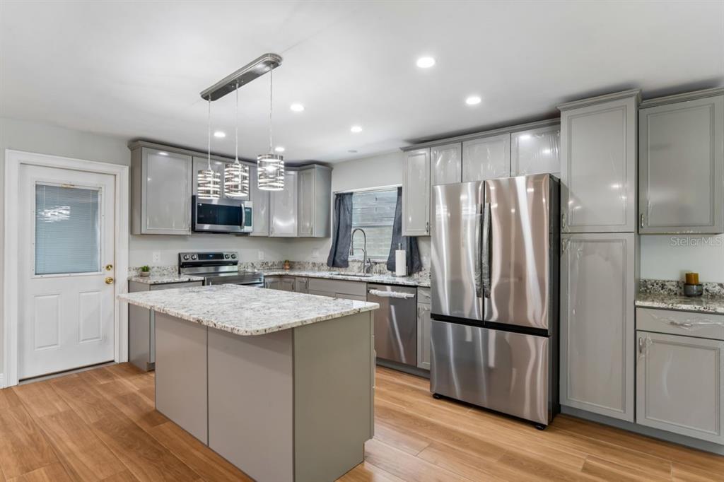 6955 Bottle Brush Drive Port Richey, FL 34668 - Photo 14 of 61 a kitchen with stainless steel appliances granite countertop a sink stove and refrigerator