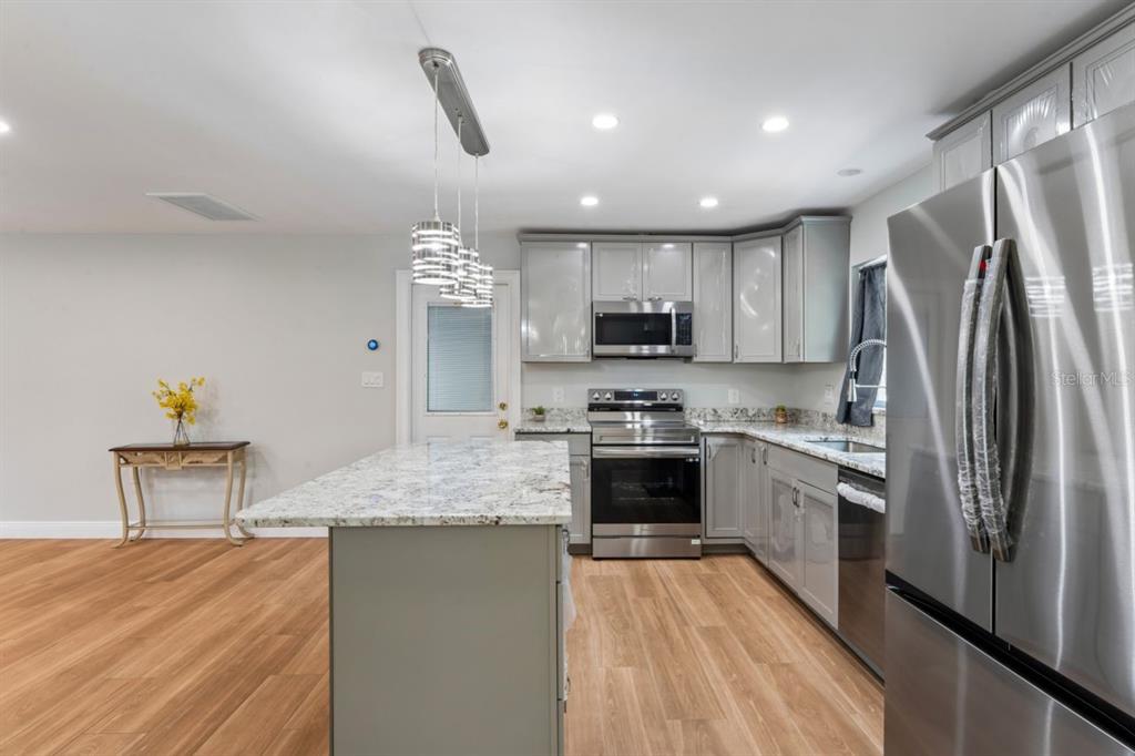 6955 Bottle Brush Drive Port Richey, FL 34668 - Photo 15 of 61 a kitchen with stainless steel appliances granite countertop a sink refrigerator and cabinets