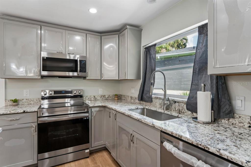 6955 Bottle Brush Drive Port Richey, FL 34668 - Photo 16 of 61 a kitchen with granite countertop a stove a microwave a sink and cabinets