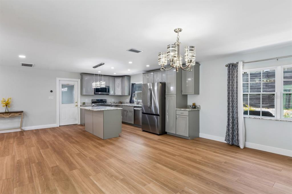 6955 Bottle Brush Drive Port Richey, FL 34668 - Photo 21 of 61 a kitchen with stainless steel appliances kitchen island wooden floors and refrigerator
