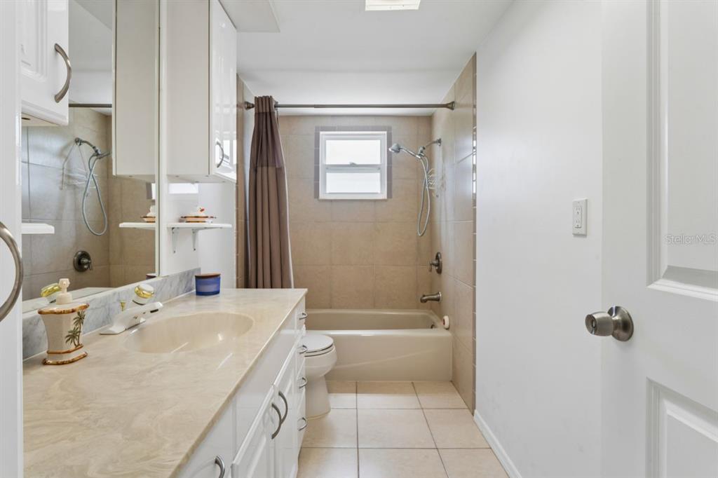 6955 Bottle Brush Drive Port Richey, FL 34668 - Photo 32 of 61 a bathroom with a granite countertop sink a mirror bathtub and shower