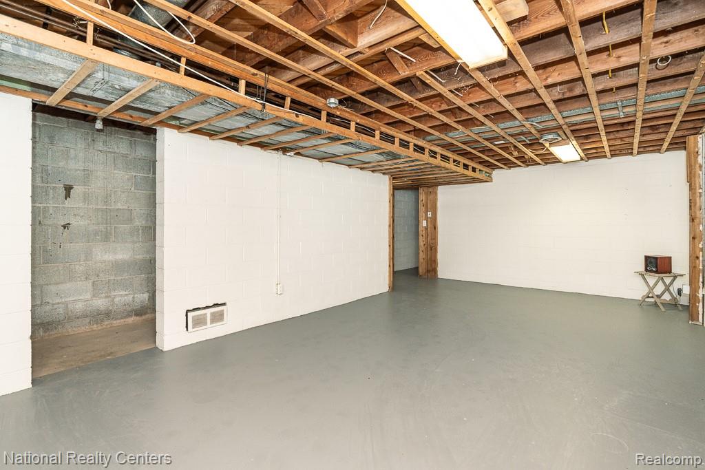 144 West Maryknoll Road Rochester, MI 48309 - Photo 37 of 38 Spacious open area with painted concrete flooring, exposed wood ceiling joists, white painted walls, and fluorescent lighting