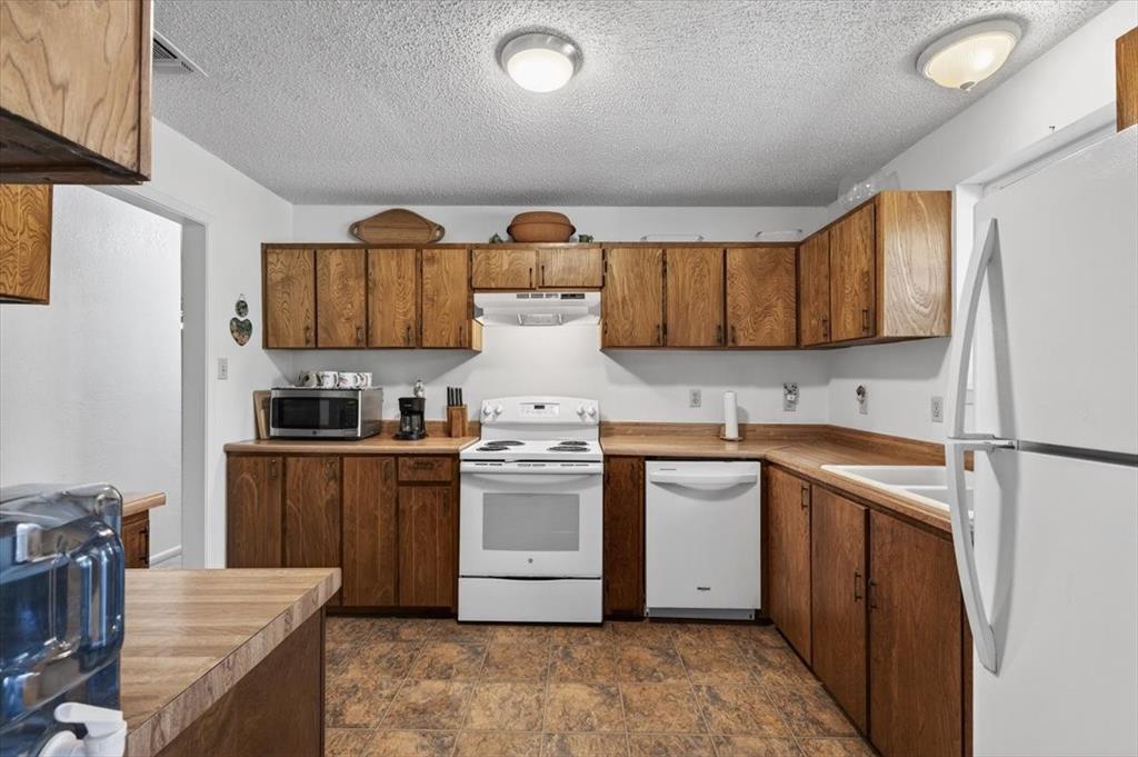 1706 Hitching Post Road Granbury, TX 76049 - Photo 13 of 40 a kitchen with stainless steel appliances granite countertop a stove a sink dishwasher and a refrigerator