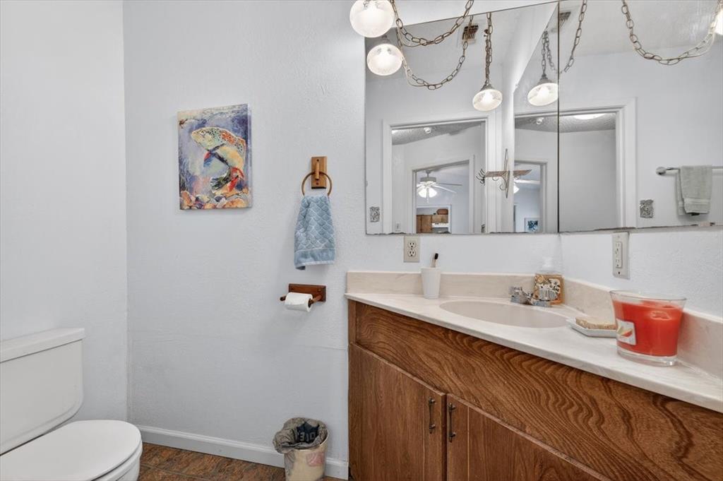 1706 Hitching Post Road Granbury, TX 76049 - Photo 16 of 40 a bathroom with a granite countertop sink a toilet and a mirror
