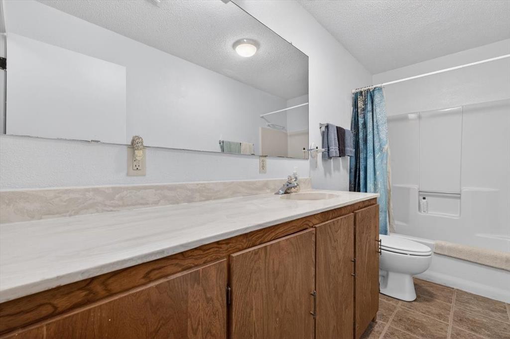 1706 Hitching Post Road Granbury, TX 76049 - Photo 20 of 40 a bathroom with a granite countertop sink a toilet and shower