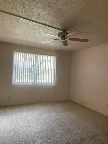 an empty room with a ceiling fan and window