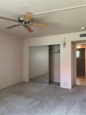 a view of a room with a ceiling fan and refrigerator in a kitchen