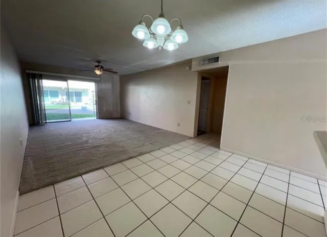 a view of a livingroom with a chandelier fan and window
