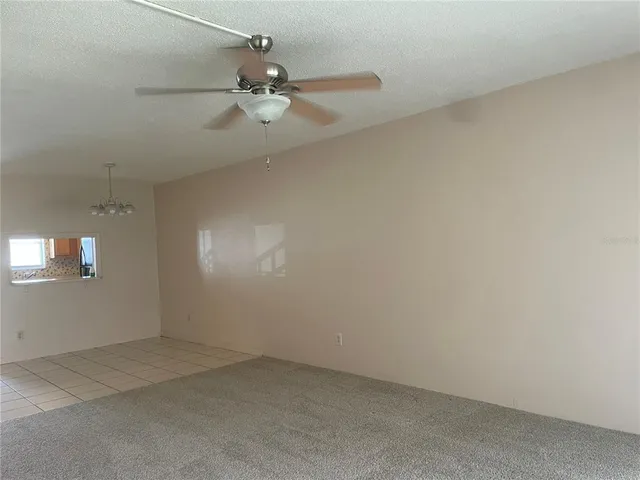 an empty room with a ceiling fan and window
