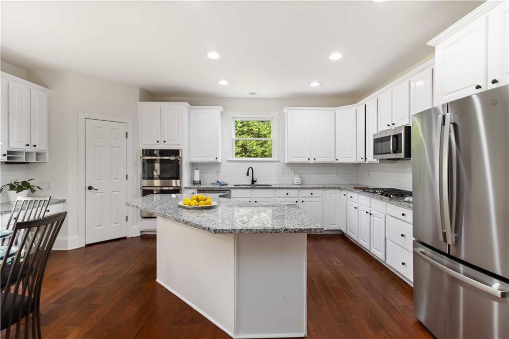 3320 Spencer Street Cumming, GA 30041 - Photo 13 of 70 a kitchen with stainless steel appliances granite countertop a refrigerator a stove top oven a sink dishwasher and wooden cabinets with wooden floor