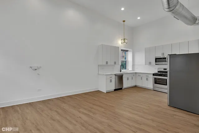 a large white kitchen with a refrigerator a sink dishwasher a oven and a stove with wooden floor