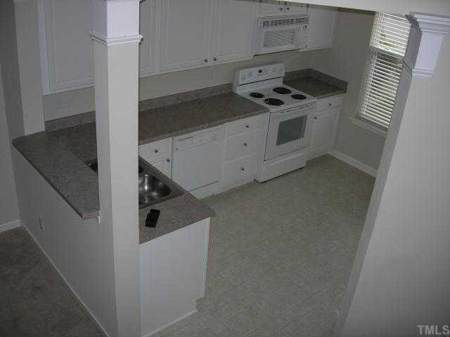 8453 Central Drive Raleigh, NC 27613 - Photo 5 of 8 a kitchen with white cabinets and white appliances