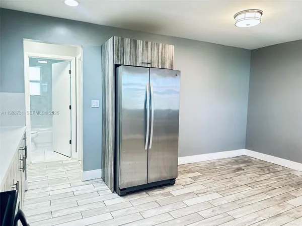 an empty room with wooden floor and bathroom view