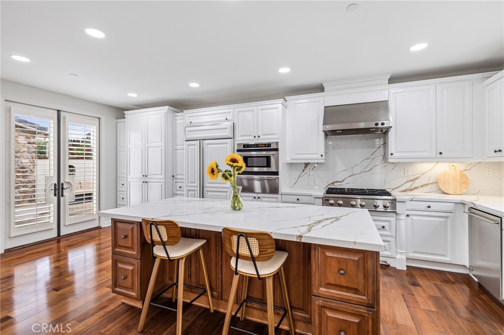 12 John Street Ladera Ranch, CA 92694 - Photo 11 of 37 a kitchen with stainless steel appliances granite countertop a stove top oven a refrigerator a sink and white cabinets with wooden floor
