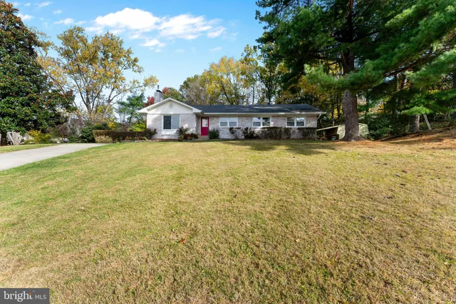 a front view of a house with a yard and large trees