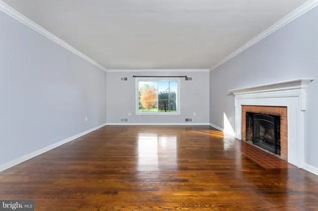 a view of empty room with wooden floor and fireplace
