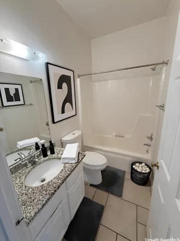 a bathroom with a granite countertop sink mirror vanity and toilet