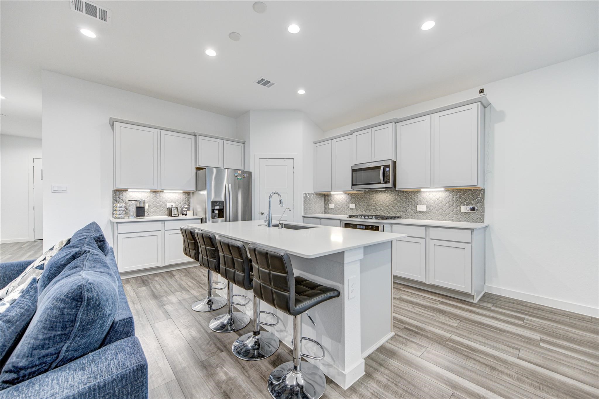 22515 Modica Rift Lane Katy, TX 77449 - Photo 17 of 34 a kitchen with stainless steel appliances granite countertop a stove top oven a sink dishwasher and a refrigerator with wooden floor