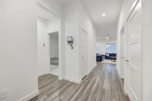 a view of a hallway with wooden floor and a bathroom