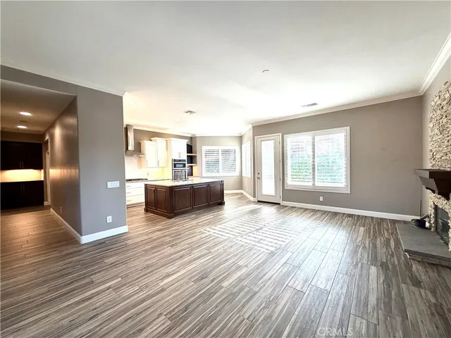 a view of a big room with wooden floor and windows