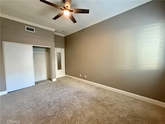 an empty room with closet and a ceiling fan