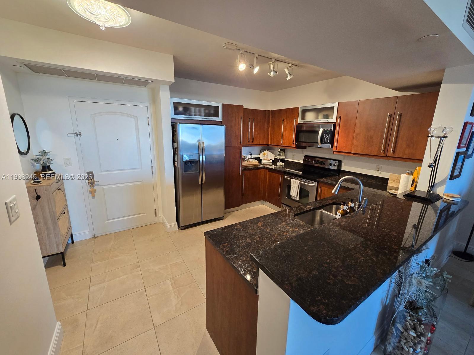 7350 Southwest 89th Street, Unit 907S Miami, FL 33156 - Photo 7 of 19 a kitchen with a sink a refrigerator and chairs