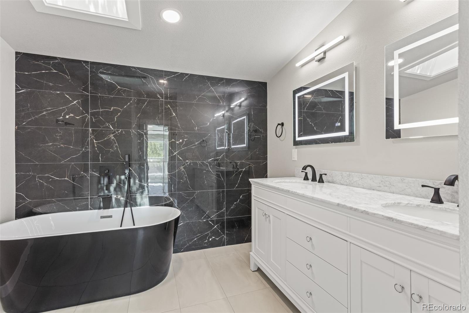 661 South Raleigh Street Denver, CO 80219 - Photo 14 of 19 a bathroom with a bathtub a mirror a sink and vanity