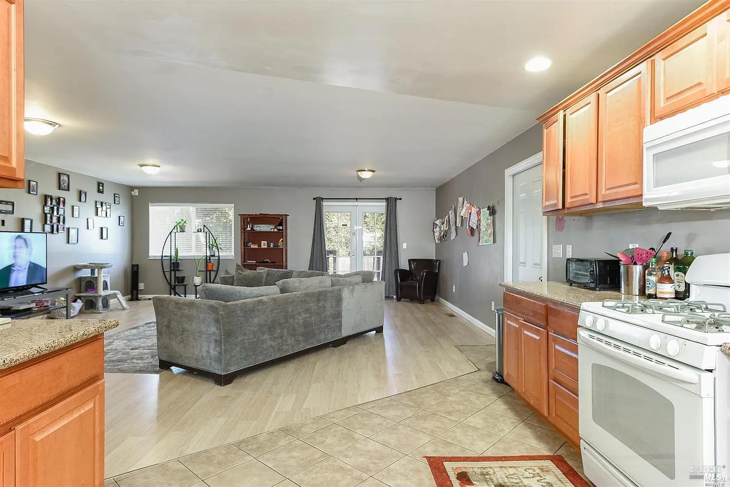 1648 Ronne Drive Santa Rosa, CA 95404 - Photo 8 of 26 a large white kitchen with stainless steel appliances granite countertop a stove a sink dishwasher and cabinets with wooden floor