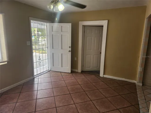 a view of an empty room with window and chandelier fan
