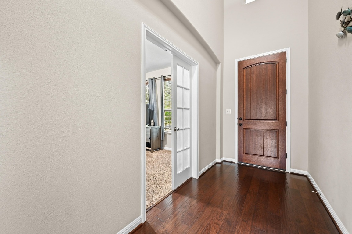154 Pettigrew Path Buda, TX 78610 - Photo 4 of 36 an empty room with wooden floor and windows