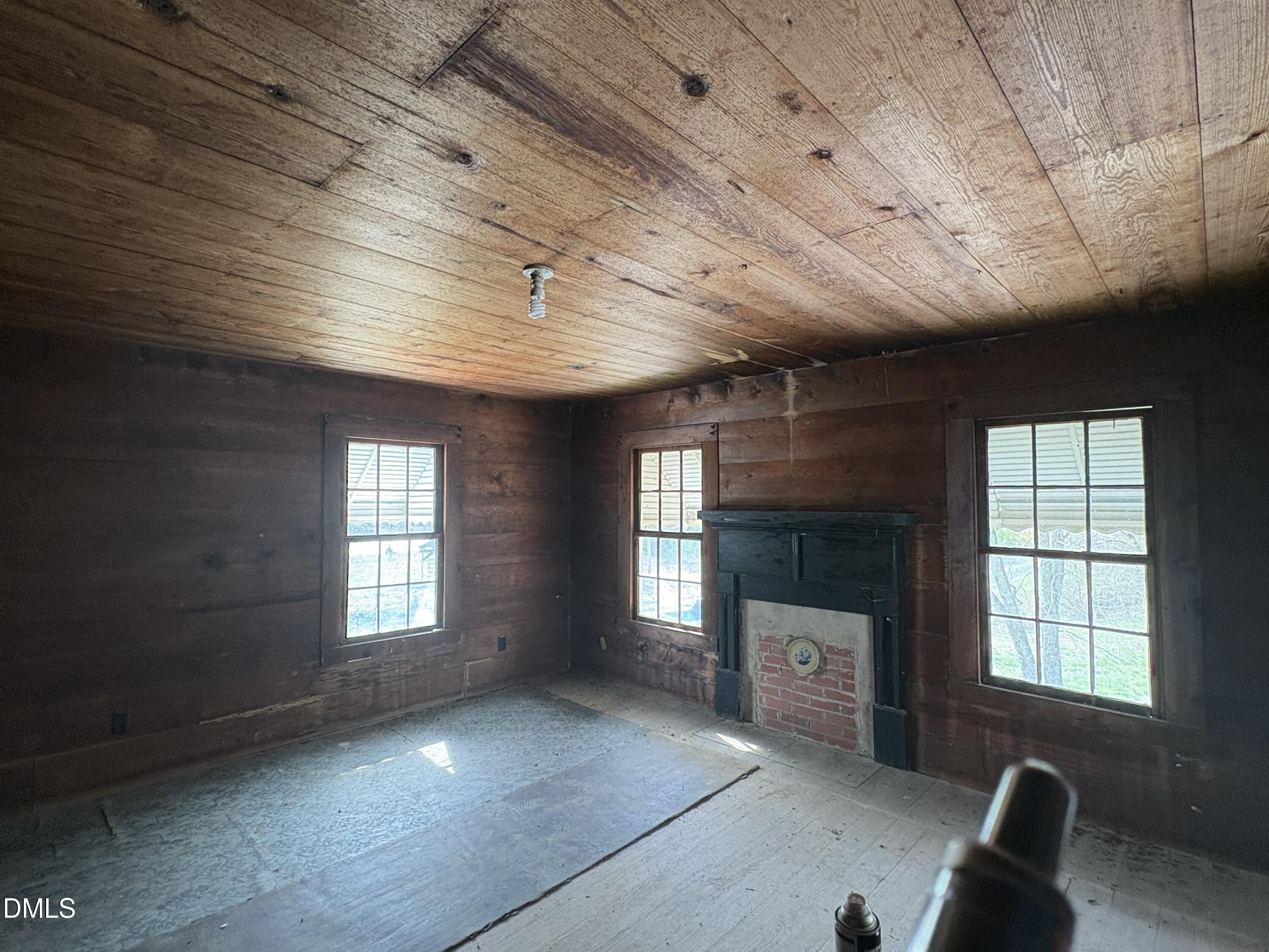 1204 Winfred Brady Road Bennett, NC 27208 - Photo 6 of 16 an empty room with a fireplace and windows