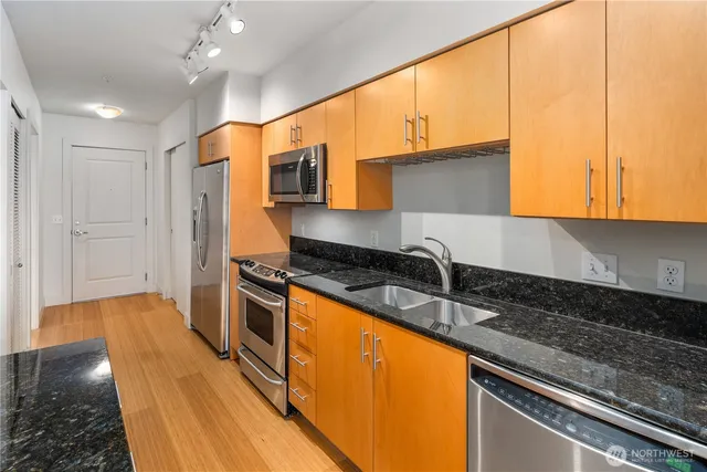 a kitchen with stainless steel appliances granite countertop a sink a stove and a refrigerator