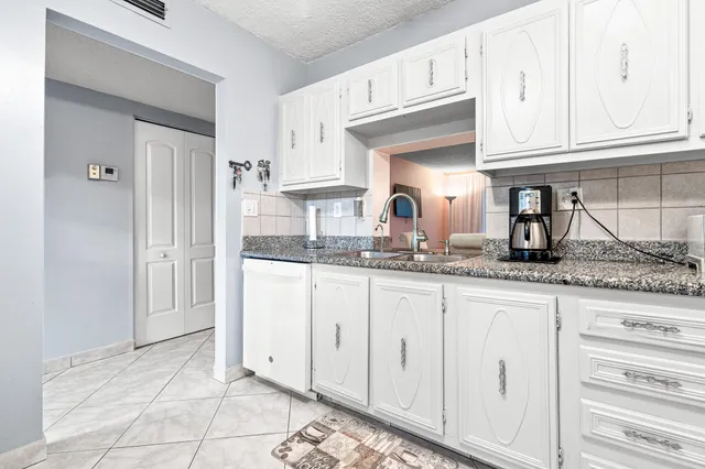 a kitchen with granite countertop white cabinets and stainless steel appliances