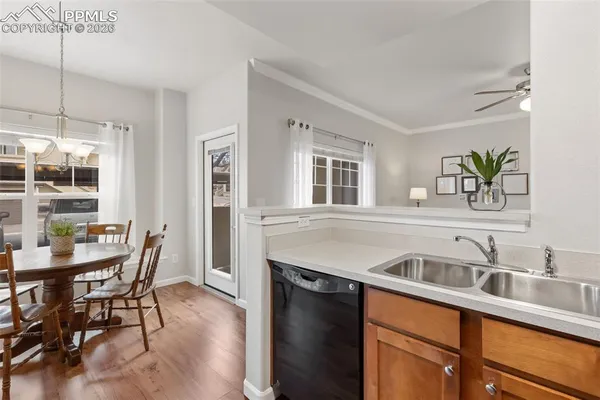 a kitchen with stainless steel appliances granite countertop a sink a stove a refrigerator a dining table and chairs with wooden floor