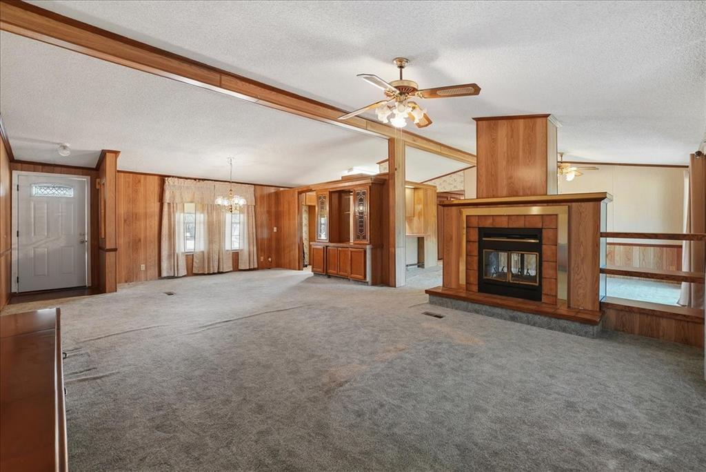 1453 Joyce Road Kaufman, TX 75142 - Photo 11 of 40 Spacious living area featuring a fireplace with brick and wood surround, wood-paneled walls, built-in cabinetry, and a ceiling fan