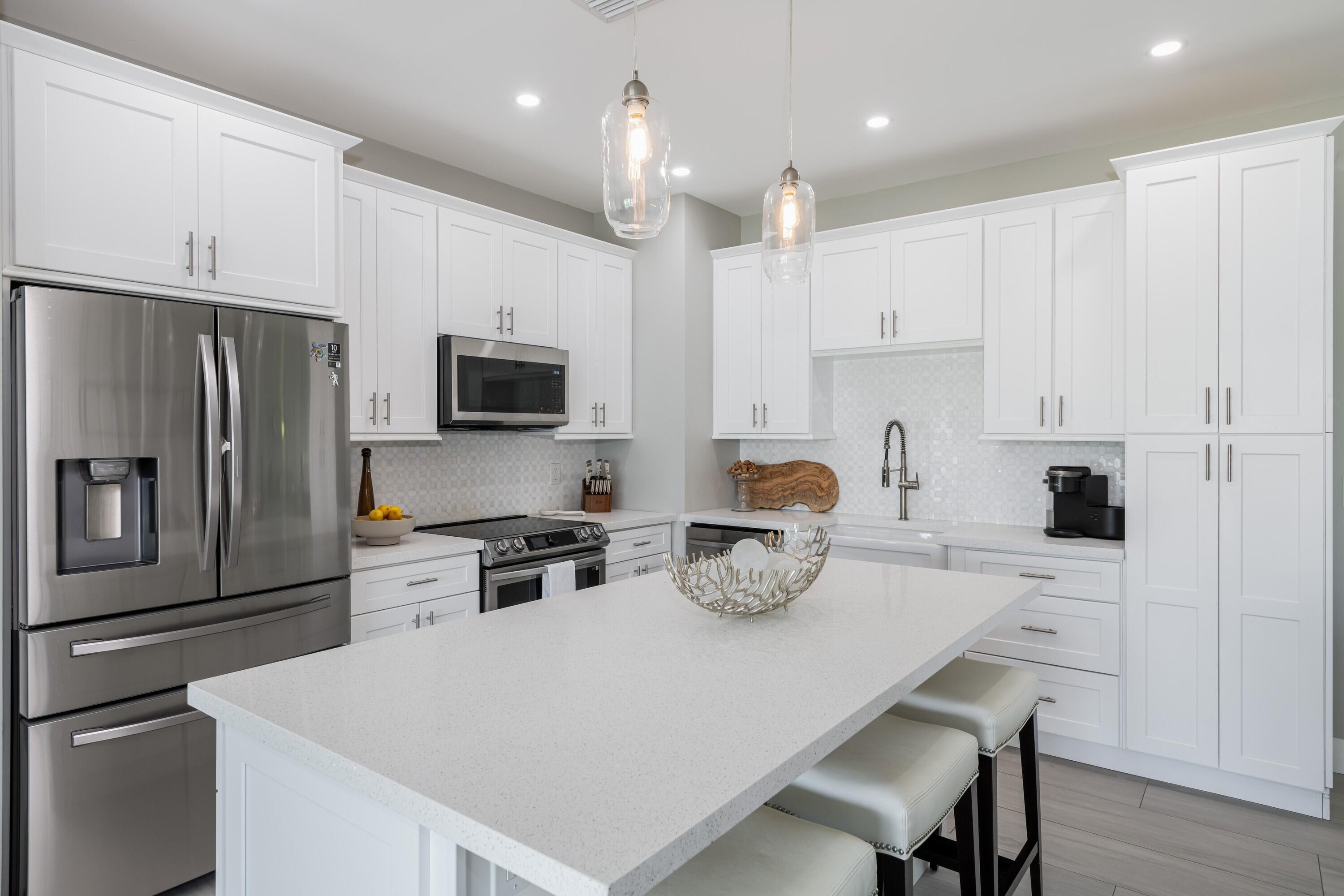 227 Corsair Road Marathon, FL 33050 - Photo 35 of 66 a kitchen with a refrigerator a stove a sink and white cabinets with wooden floor