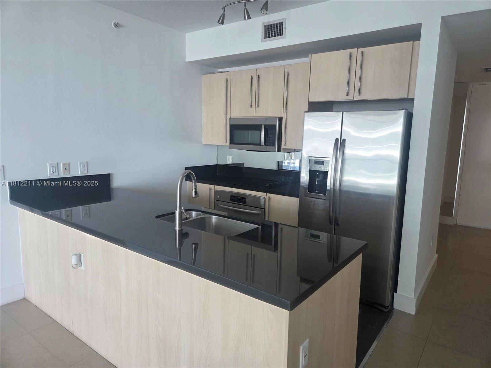 79 Southwest 12th Street, Unit 2409 Miami, FL 33130 - Photo 3 of 13 a kitchen with granite countertop a refrigerator and a sink