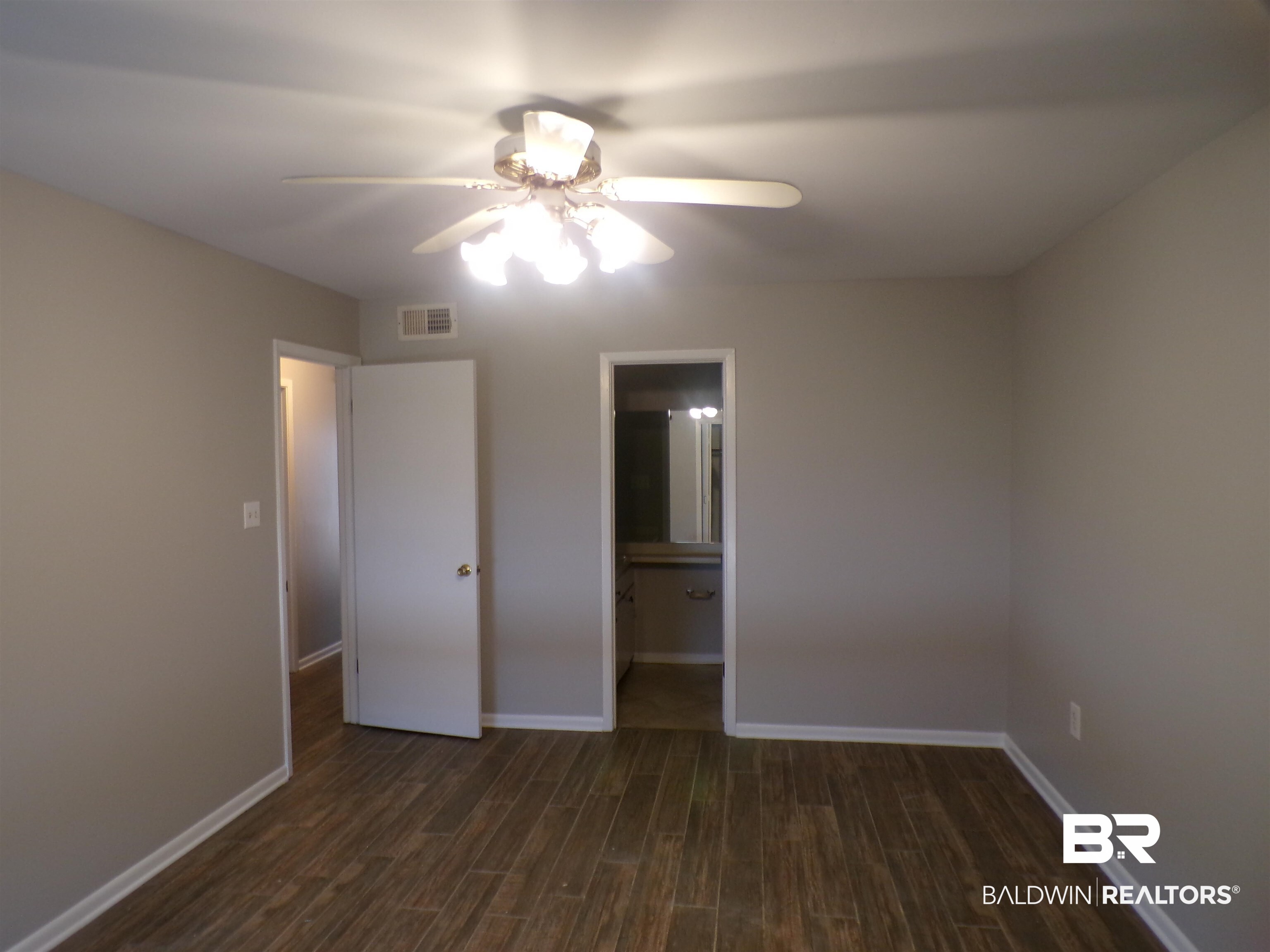1152 North Alston Street, Unit 1152 Foley, AL 36535 - Photo 12 of 16 Spacious room featuring wood-finish flooring, light gray walls, and a ceiling fan with integrated lighting