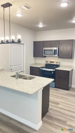 a kitchen with stainless steel appliances granite countertop a sink a stove and a wooden floor