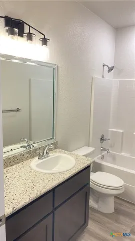 a bathroom with a granite countertop sink a toilet and mirror