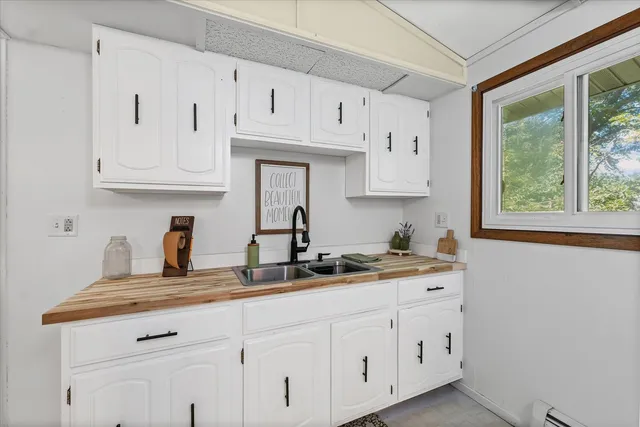a kitchen with white cabinets and a window