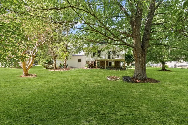 a view of a house with a big yard and large trees