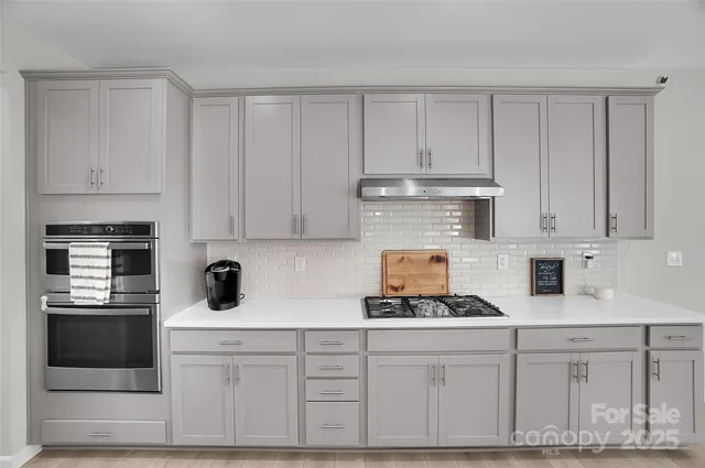 a kitchen with stainless steel appliances a sink a stove top oven a counter space and cabinets