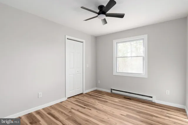 a view of empty room with wooden floor and fan