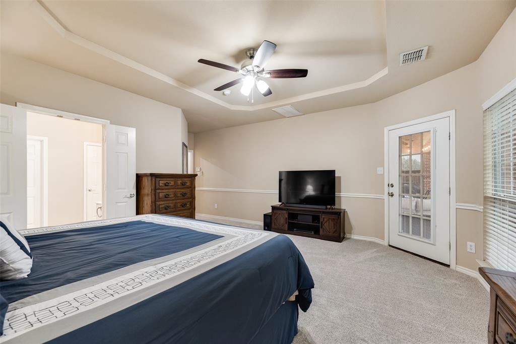 11920 Vienna Apple Road Fort Worth, TX 76244 - Photo 21 of 40 Primary bedroom with new carpet, tiered ceiling, door to the back patio and ensuite bathroom at 11920 Vienna Apple in Villages of Woodland Springs community in North Fort Worth
