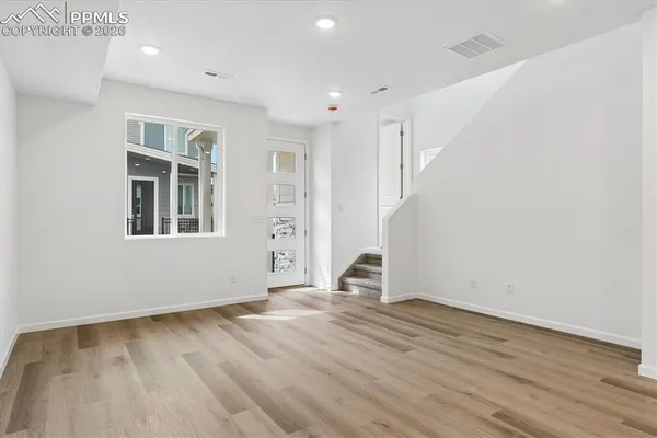an empty room with wooden floor and windows