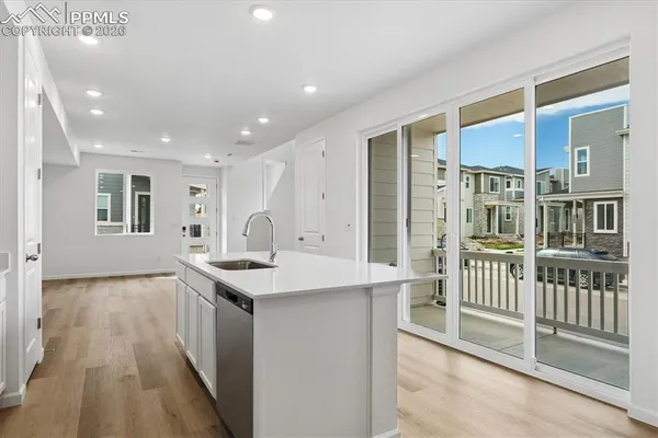 a view of a kitchen with kitchen island wooden floor and a sink