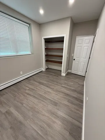 an empty room with wooden floor closet and windows