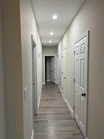 a view of a hallway with wooden floor and closet area